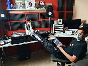Samet DJ Uncle S im heimischen Tonstudio, Füße hochgelegt und Mundschutz aufgesetzt